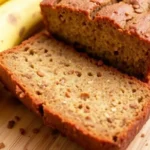 Moist banana bread loaf sliced on a wooden board, banana bread recipe no butter