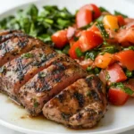 Sliced grilled steak served with a tomato and spinach salad.